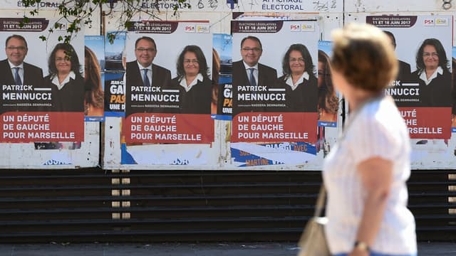 Une femme passe devant les affiches de campagne de Patrick Mennucci, candidat socialiste battus aux élections législatives, le 28 mai 2017 à Marseille. 