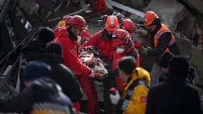 Des secouristes transportent un jeune homme secouru sur un brancard à travers les décombres des bâtiments de Kahramanmaras, l'épicentre du séisme en Turquie, le 7 février 2022.