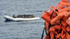 Des migrants assis dans un bateau pneumatique lors d'une opération de sauvetage au large des côtes libyennes, le 5 novembre 2016