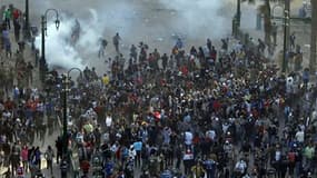 Des opposants au président égyptien Mohamed Morsi fuient les gaz lacrymogènes de la police antiémeute près de la place Tahrir, au Caire. Des milliers de manifestants ont affronté la police vendredi au Caire, ainsi que dans plusieurs grandes villes d'Egypt