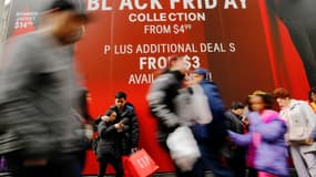 Des passants devant une affiche faisant la promotion du Black Friday, le 25 novembre 2016 à New York. 