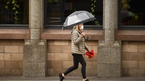 Un femme portant un masque et marchant dans les rues désertes de la ville de Manchester au Royaume-Uni