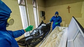 Des employés de Los Olivos Funerales en combinaison intégrale de protection s'occupent du corps d'une personne décédée du coronavirus, le 1er juin 2020 à Mexico
