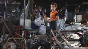 Une petite fille palestinienne cherche des objets récupérables parmi les débris après qu'une frappe aérienne israélienne a touché l'école Mussa bin Nusseir de l'UNRWA, qui sert d'abri aux personnes ayant quitté leur maison dans le territoire palestinien assiégé, dans le district de Daraj de la ville de Gaza (Palestine), le 20 mai 2025.