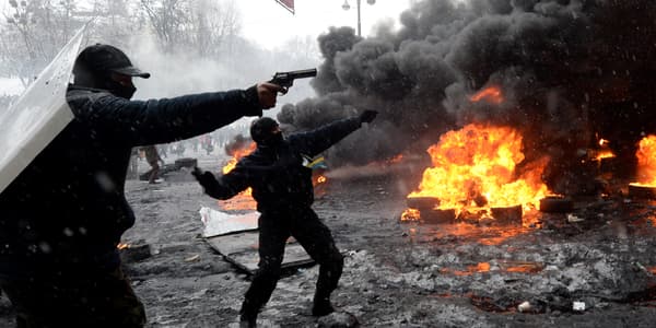 Un manifestant point un pistolet sur les policiers, mercredi 22 janvier, à Kiev.
