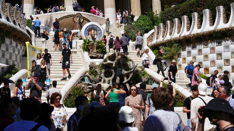 Des touristes visitent l'escalier monumental du parc Guell à Barcelone, le 13 avril 2024.