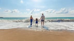 Une famille à la plage au bord de l'eau. (Illustration)