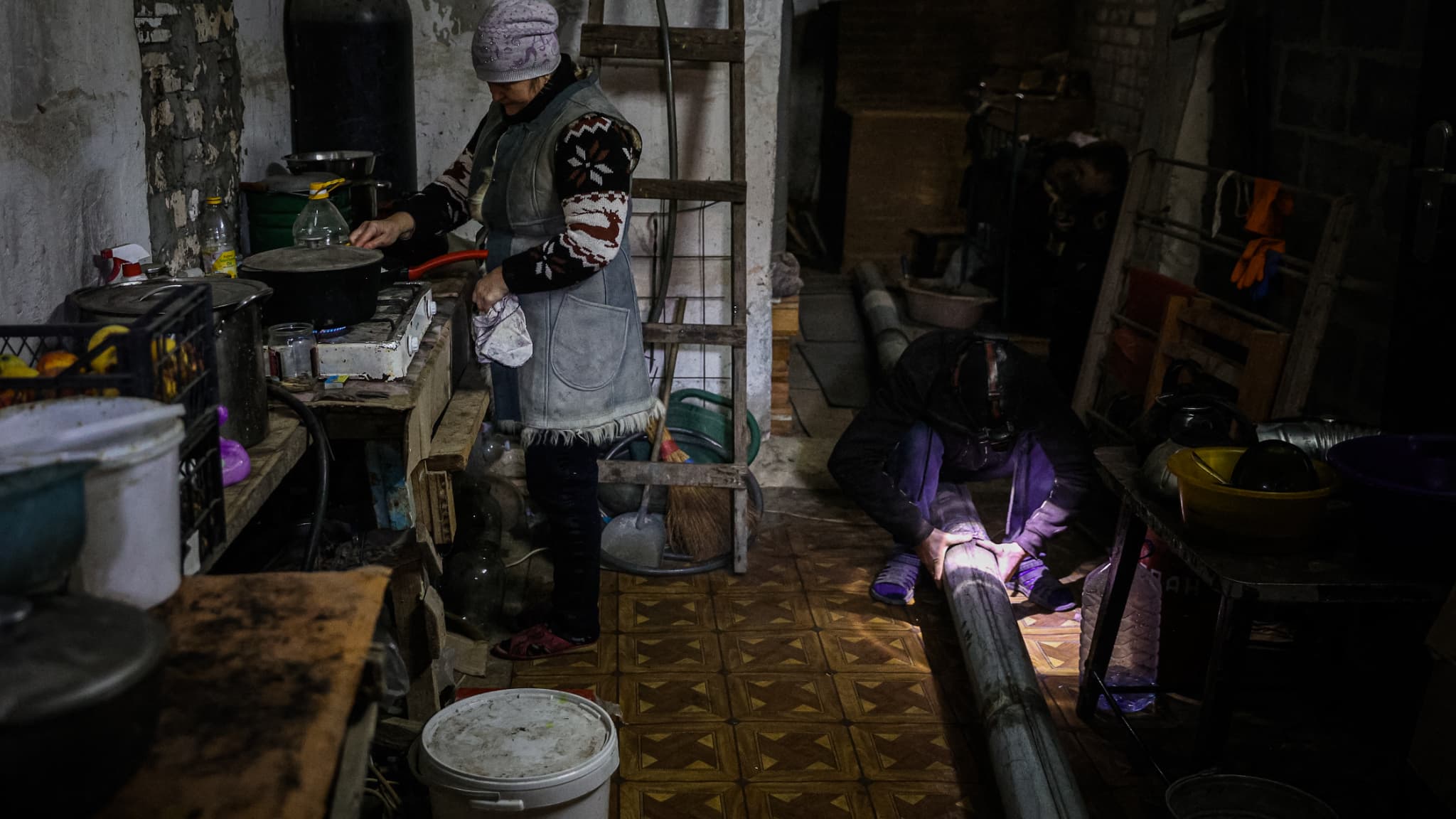 Une femme cuisine réfugiée dans une cave à Bakhmout, visée par des frappes russes, en Ukraine, le 1er décembre 2022