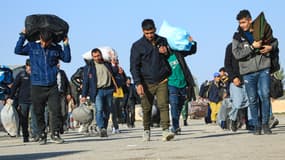 Des immigrants afghans expulsés d'Iran transportent leurs affaires vers un camp