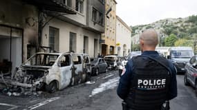 Un policier regarde des voitures incendiées devant le commissariat de Cavaillon, dans le Vaucluse, le 9 octobre 2024