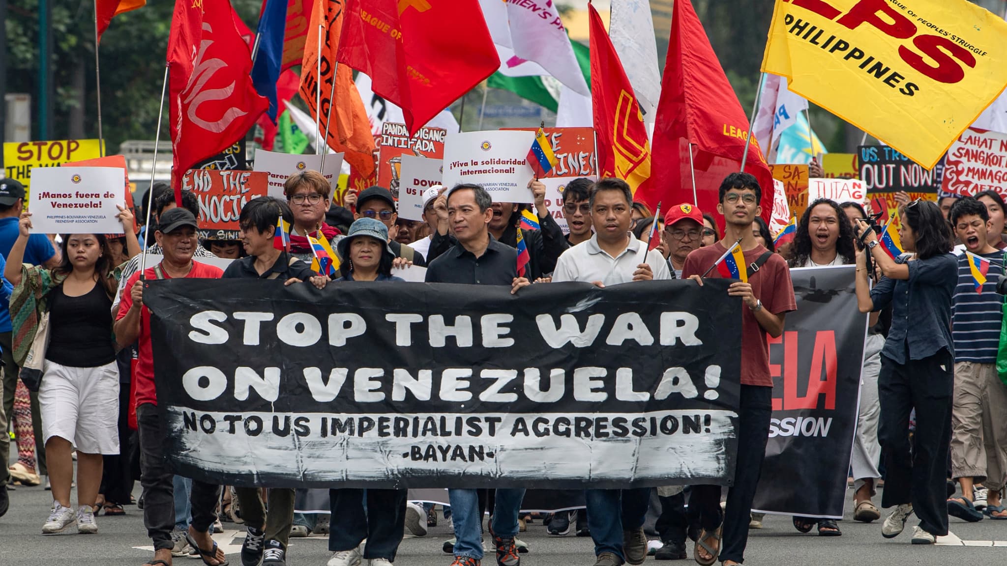 Des manifestants brandissant des drapeaux et une banderole défilent lors d'une manifestation condamnant l'attaque américaine contre le Venezuela et la capture du dirigeant vénézuélien Nicolás Maduro, près de l'ambassade américaine à Manille (Philippines), le 5 janvier 2026. 