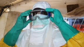 Un membre de Médecins sans frontières (MSF) s'équipe d'une combinaison de protection à l'hôpital de Conakry, capitale de la République de Guinée, où des personnes contaminées par Ebola sont soignées, le 28 juin 2014.