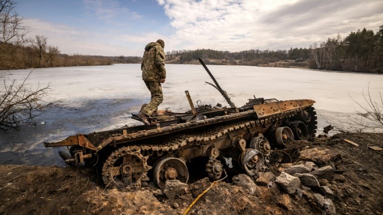 Un militaire ukrainien se tient près d'un tank russe détruit dans la ville de Trostyanets en Ukraine le 29 mars 2022