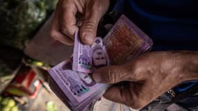 Des billets syriens de 2.000 livres à l'effigie de l'ancien président syrien Bachar al-Assad sont comptés alors que les gens font leurs achats dans un marché le 17 juin 2025 à Damas, en Syrie.