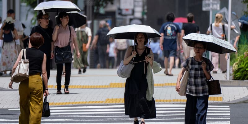 Des piétons se protègent du soleil à Tokyo le 9 juillet 2024 alors que le pays subit une vague de chaleur rare et intense