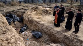 Des prêtres prient devant une fosse commune avec de nouveaux cadavres, dans la petite ville ukrainienne de Boutcha, le 7 avril 2022
