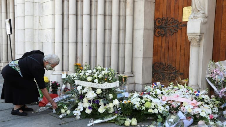 Une femme dépose des fleurs devant la basilique Notre-Dame à Nice en hommage aux victimes de l'attentat, le 30 octobre 2020 