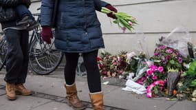 Une femme déposant des fleurs devant l'immeuble où l'auteur présumé de deux attaques meurtrières a été abattu par la police