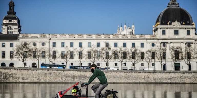 Un homme transporte ses enfants dans la benne avant de son vélo-cargo, le 23 mars 2022 à Lyon