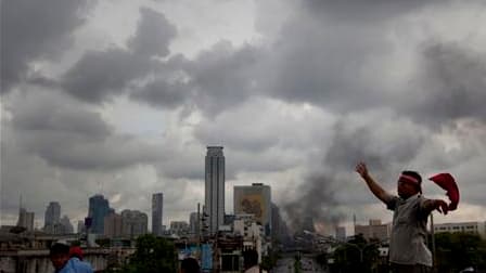 Manifestants antigouvernementaux près d'une barricade en flammes à Bangkok, dimanche. Le Premier ministre thaïlandais, Abhisit Vejjajiva, a déclaré que son gouvernement étudiait la possibilité de décréter un couvre-feu dans la capitale après trois jours d