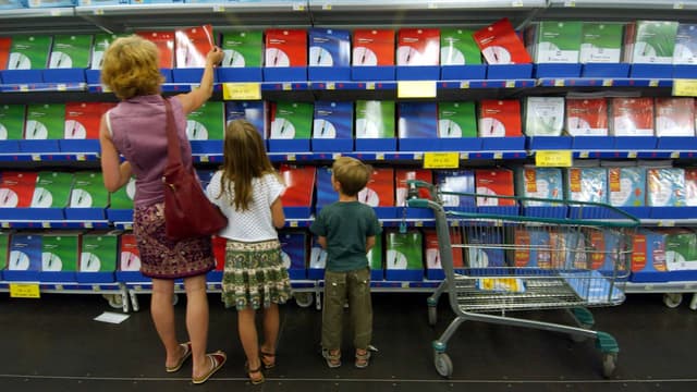 Une mère et ses deux enfants font leus courses dans une grande surface.