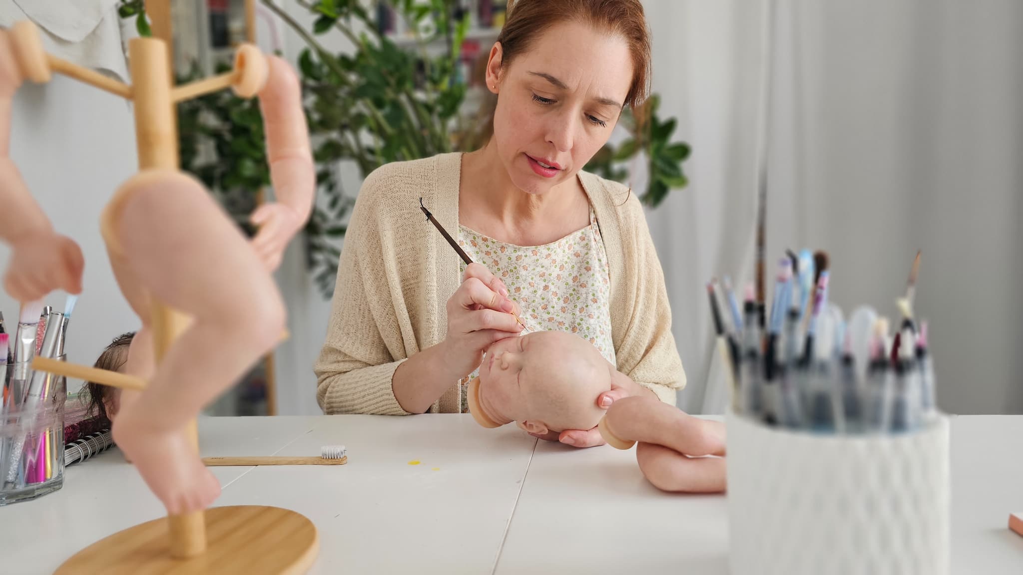 Adeline Ginguené en train de peindre la tête d'une poupée reborn dans son atelier au Mans.