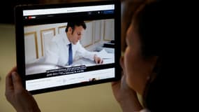 Une femme regarde sur une tablette la première vidéo d'Emmanuel Macron comme candidat à la présidentielle, le 4 mars 2022 à Paris