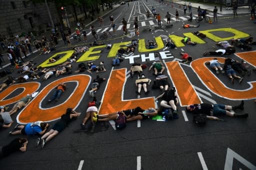 Des manifestants allongés autour d'une inscription invitant à "couper les vivres de la police", le 6 juin 2020, à Washington Des manifestants allongés autour d'une inscription invitant à "couper les vivres de la police", le 6 juin 2020, à Washington