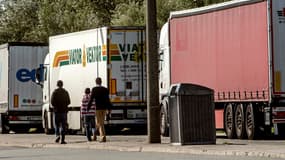 Des migrants marchent à côté de camions stationnés à Calais, le 5 août 2014.