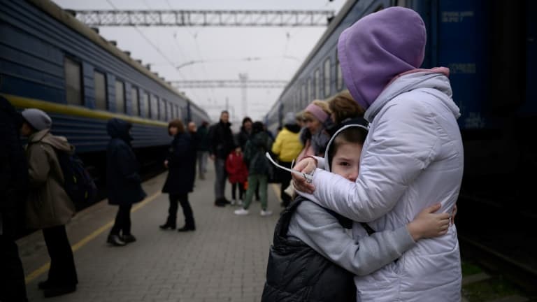 Une femme étreint un enfant avant le départ d'un train de la gare de Zaporijia dans le sud de l'Ukraine le 17 avril 2022