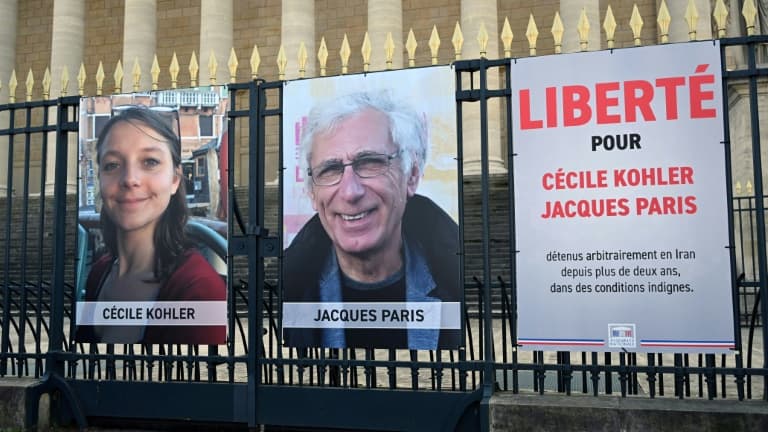 Les portraits de Cécile Kohler et de Jacques Paris, emprisonnés en Iran, accrochés aux grilles de l'Assemblée nationale à Paris, le 25 mars 2025
