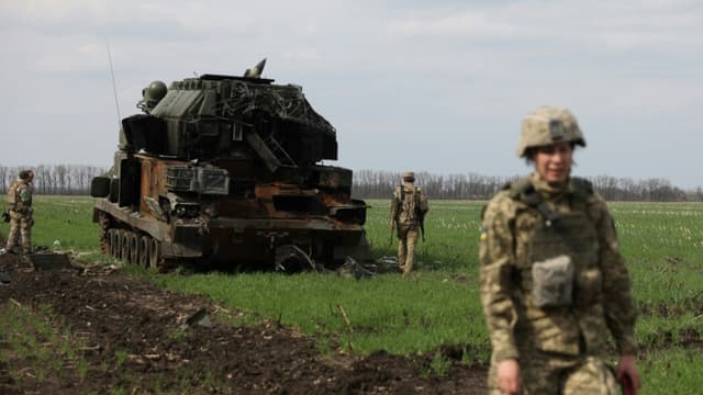 Des soldats ukrainiens s'affairent près d'un véhicule militaire russe détruit près du village de Gusarovka village, dans la région de Kharkiv, dans l'est de l'Ukraine, le 16 avril 2022