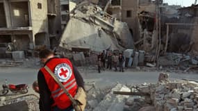 Un bénévole de la Croix rouge internationale parcourt des ruines à Douma, dans la Ghouta orientale le 5 mars 2018. -