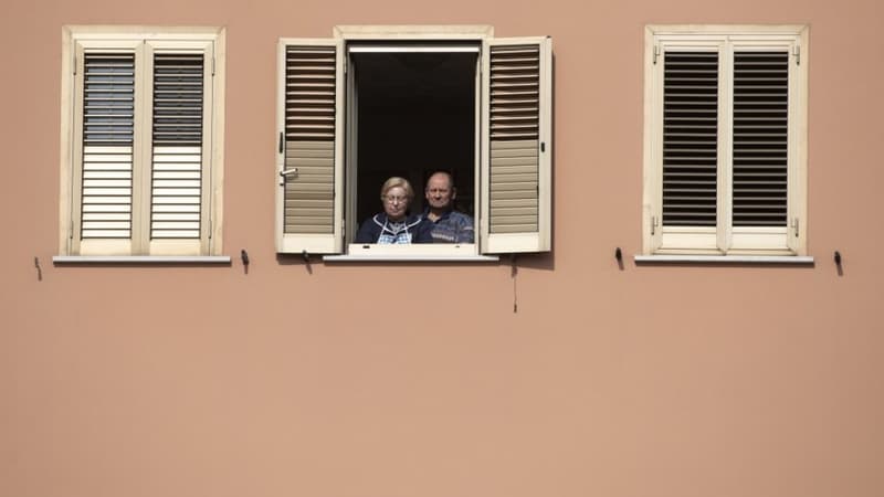 Image d'illustration - Deux personnes regardant dehors depuis leur fenêtre - Tiziana FABI / AFP