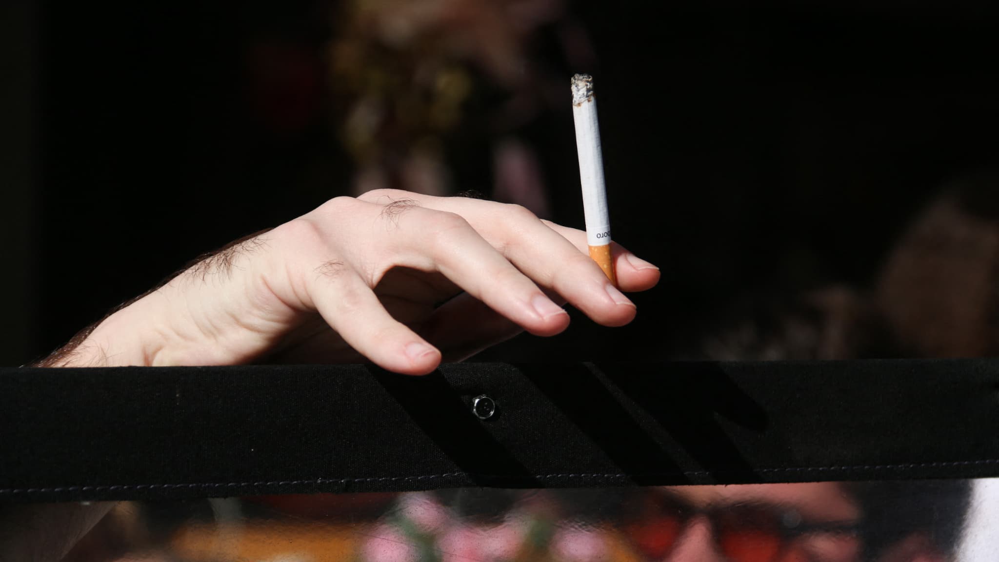 Une personne en train de consommer une ciagrette en extérieur. 