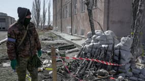 Un soldat ukrainien à côté de fusils d'assaut récupérés sur le site militaire de Mykolaïv en Ukraine, après le bombardement de vendredi 18 mars 2022