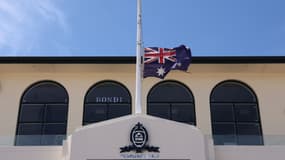 Le drapeau australien flotte en berne au Bondi Surf Bathers Life Saving Club, près de la promenade de Bondi Beach, où des personnes en deuil ont déposé des fleurs en hommage aux victimes de la fusillade qui s'est produite à cet endroit le 14 décembre, à Sydney, le 18 décembre 2025.