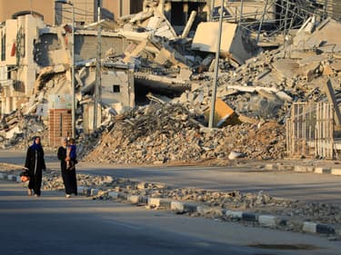 Des Palestiniens déplacés passent devant des bâtiments détruits dans le camp de réfugiés d'al-Bureij, dans le centre de la bande de Gaza, le 12 juin 2024, au milieu du conflit en cours entre Israël et le groupe militant du Hamas.