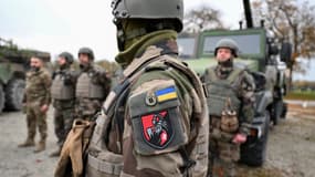 Des soldats ukrainiens de la 155e Brigade mécanisée se tiennent à côté de véhicules militaires lors d'un exercice d'entraînement de l'armée française, au camp militaire de Mourmelon-le-Grand, le 14 novembre 2024.