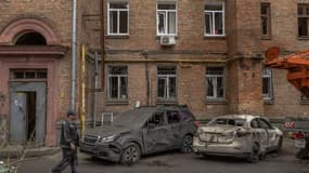 Un homme passe devant des voitures et un immeuble résidentiel endommagés à la suite d'une attaque de drone russe, à Kiev, le 26 septembre 2024, dans le cadre de l'invasion russe en Ukraine.