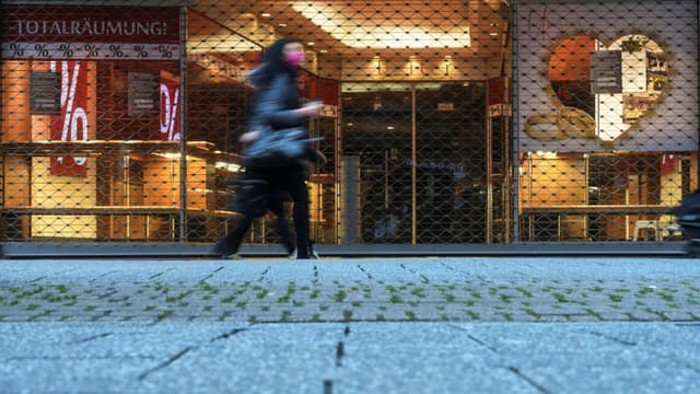 Une femme passe devant un magasin fermé dans une zone commerçante de Cologne, le 4 janvier 2021