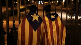 Deux jeunes Espagnols pro-indépendantistes portent le drapeau catalan devant le Parlement catalan à Barcelone, le 26 octobre 2017