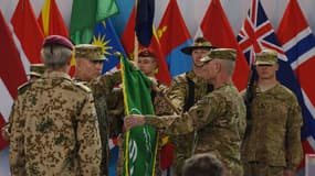 Le général américain John Campbell (le second depuis la gauche) déplie un drapeau lors d'une cérémonie de fin de mission de la force de l'Otan en Afghanistan (Isaf), dimanche 28 décembre 2014 à Kaboul.