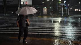 Un homme avec un parapluie traverse une rue à Tokyo, le 8 septembre 2019, alors que le typhon Faxai s'abat sur Tokyo.