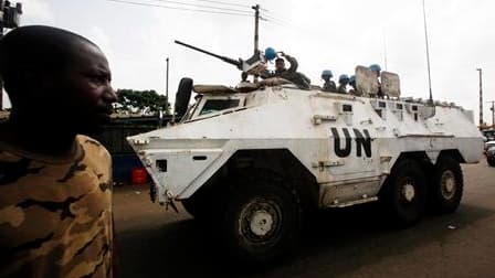 Soldat fidèle à Alassane Ouattara près d'une patrouille de l'Onuci (l'Opération des Nations unies en Côte d'Ivoire) dans la banlieue nord d'Abidjan. Une accalmie relative prévaut dimanche à Abidjan où la population en a profité pour se réapprovisionner au