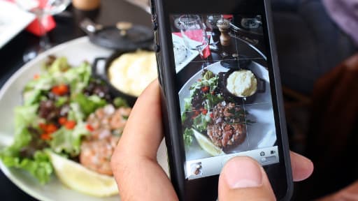 Image prise le 19 juin 2012, montrant un homme prenant en photo son plat dans un restaurant parisien.