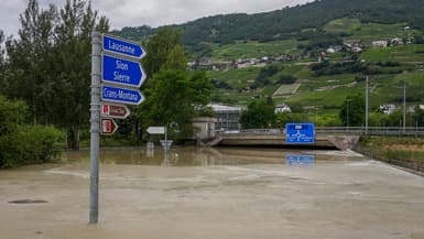 Des panneaux routiers sur une route inondée près de Sierre, à l'ouest de la Suisse, ce dimanche 30 juin.