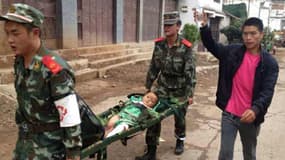 Des secouristes transportent un blessé après un tremblement de terre survenu dimanche dans le sud-ouest de la Chine.