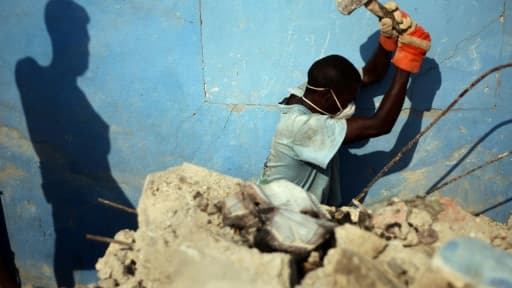 Des Haïtiens déblayent les ruines du tremblement de terre dans une rue de Port-au-Prince le 8 janvier 2011, un an après le séisme