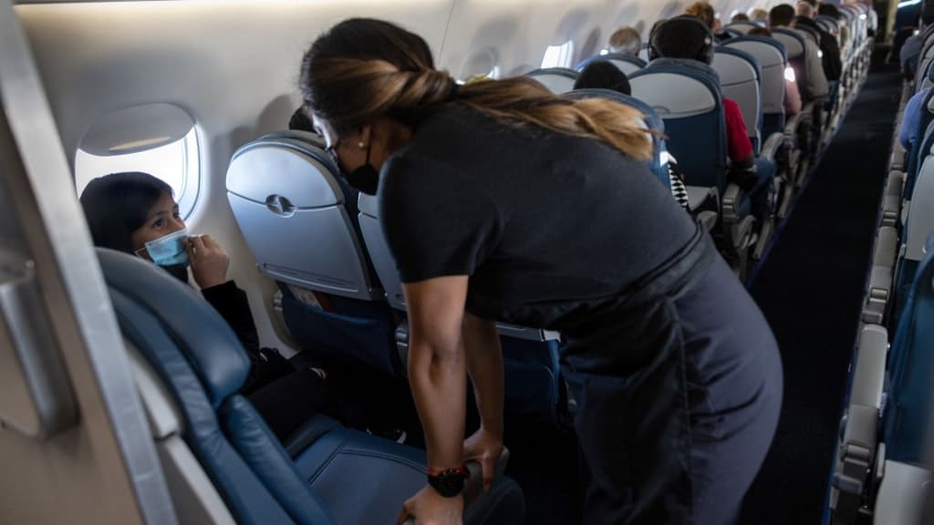 Une hôtesse de l'air en train de discuter avec une jeune fille à bord d'un vol vers les États-Unis en avril 2021.